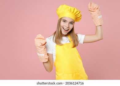 Teen Girl Chef Cook Confectioner Baker Housewife In Yellow Apron White T-shirt Toque Cap Kitchen Mitten Potholder Do Winner Gesture Clench Fist Isolated On Pink Background Studio Portrait Food Concept