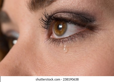 Teen girl crying, with a tear drop running down her cheek.  