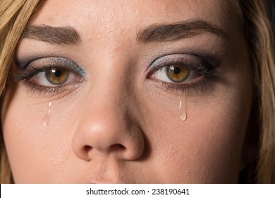 Teen girl crying, with a tear drop running down her cheek.  