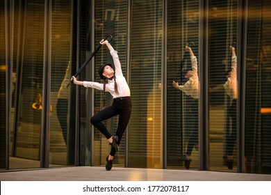 Teen girl dancing modern jazz among golden reflections in the mirror walls