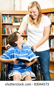 Teen Girl And Disabled Boy In The School Library.