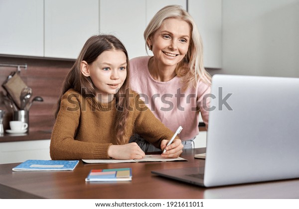 Teen girl distance learning virtual distance\
online class on video call virtual lesson with mother, studying at\
home using laptop computer. Parent or tutor helping child daughter\
with remote education