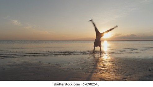 Teen Girl Doing Cartwheel On A Beach In Sunset Time Motion Blur