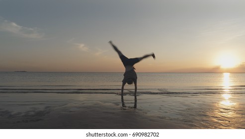 Teen Girl Doing Cartwheel On A Beach In Sunset Time Motion Blur