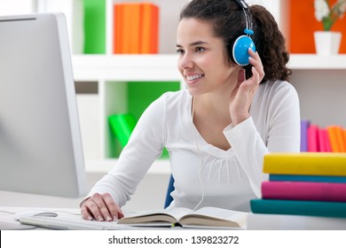 teen girl doing her homework online and listening to headphones.