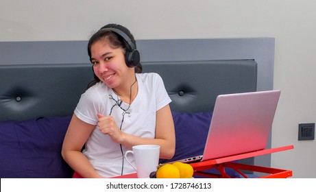 A teen girl enjoys to learn from home while listening to music on the bed. - Powered by Shutterstock