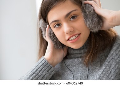 Teen girl with fluffy headphones listen music in white room - Shutterstock ID 604362740