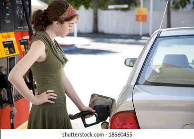 Teen Girl At The Gas Station Filling Up The Fuel Tank In Her Gas Efficient Car.