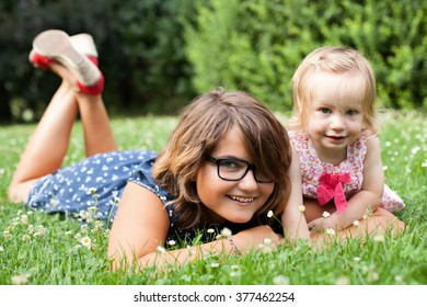 Teen girl and her toddler sister on the grass