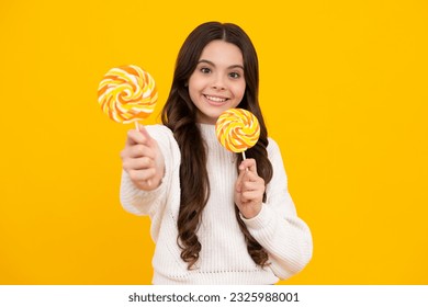 Teen girl hold lollipop caramel on yellow background, candy shop. Teenager with sweets suckers. Happy face, positive and smiling emotions of teenager girl.