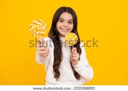 Teen girl hold lollipop caramel on yellow background, candy shop. Teenager with sweets suckers. Happy face, positive and smiling emotions of teenager girl.
