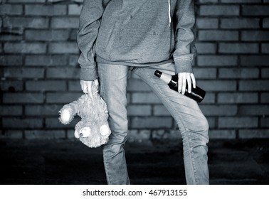 Teen Girl Holding A Beer Bottle And A Teddy Bear In The Alley