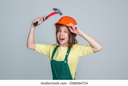 Teen Girl Laborer In Protective Helmet And Uniform On Grey Background Use Hammer, Protection