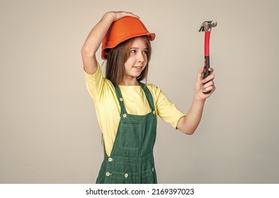 Teen Girl Laborer In Protective Helmet And Uniform On Grey Background Use Hammer, Worker