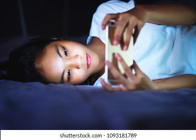 Teen Girl Lying In Bed At Night And Using Smart Phone