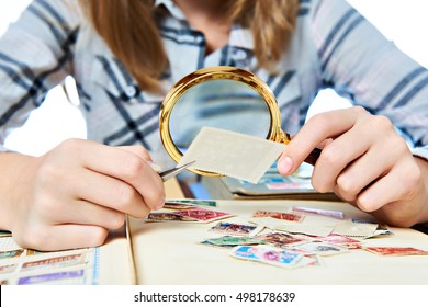 Teen girl with magnifier looks his stamp collection - Powered by Shutterstock