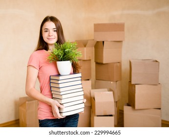 Teen Girl Moving House To College, Holding Pile Books And Plant