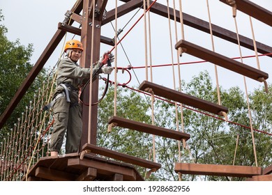 Teen Girl On A Rope Course In A Treetop Adventure Park Passing Hanging Ropes Obstacle