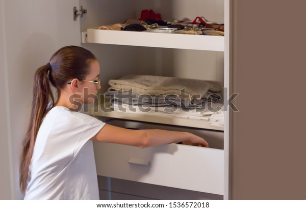 Teen girl order the linens in the\
closet. Concept of order, cleanliness in wardrobe and home,\
collaboration of the teenagers to keep the home environments\
tidy.