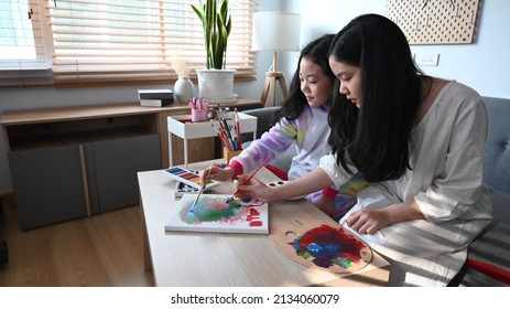 Teen Girl Painting Picture With Her Young Sister In Living Room.