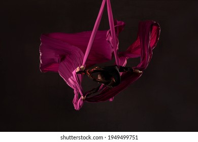 Teen girl performing acrobatic split over head on aerial silks - Powered by Shutterstock