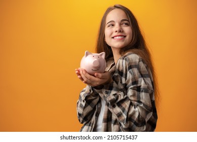 Teen Girl With Piggy Bank On Yellow Background.
