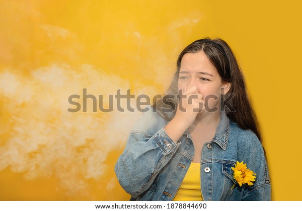 Teen girl pinch her nose because toxic fumes\
from car, bad smell,air pollution,dust allergies or sinus\
ingection, female teenage rubbing nose suffer from allergic in\
city. Passive smoking\
concept.