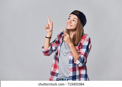 Teen Girl Pointing To The Side Up At Empty Copy Space, Over Grey Background