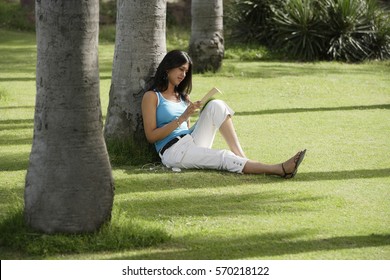 Teen Girl Reading Book In Park