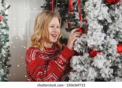 Teen girl in a red sweater near the Christmas tree