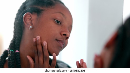 Teen Girl Removing Acne Zit In Front Of Mirror. Black African Ethnicity