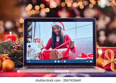 Teen girl in Santa hat opening gift box in remote chat on laptop computer screen Merry Christmas table background. Xmas online virtual party celebration, Happy New Year present unpacking videocall. - Powered by Shutterstock