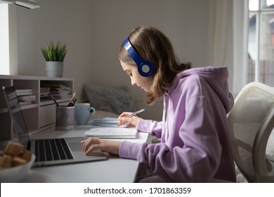 Teen girl school pupil wearing headphones studying online from home making notes. Teenage student distance learning on laptop doing homework, watching listening video lesson. Remote education concept - Shutterstock ID 1701863359