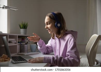 Teen girl school pupil wears headphones conference calling studying online with remote tutor from home. Teenage student using laptop talking in webcam video chat learning lesson with distance teacher.