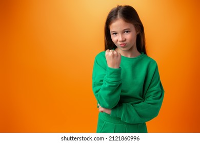 Teen Girl Showing Off Muscles Biceps Against Orange Background