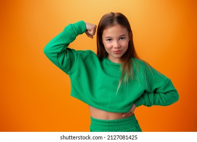 Teen Girl Showing Off Muscles Biceps Against Orange Background