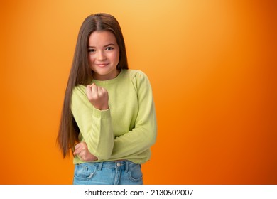 Teen Girl Showing Off Muscles Biceps Against Orange Background