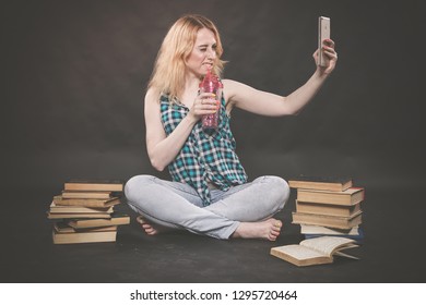 Teen Girl Sitting On The Floor Next To Books, Does Not Want To Learn, Drinking Juice And Taking A Selfie On The Smartphone