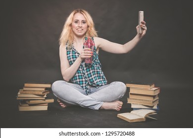 Teen Girl Sitting On The Floor Next To Books, Does Not Want To Learn, Drinking Juice And Taking A Selfie On The Smartphone