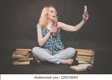 Teen Girl Sitting On The Floor Next To Books, Does Not Want To Learn, Drinking Juice And Taking A Selfie On The Smartphone