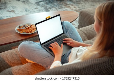 Teen Girl Sitting On Sofa In Lotus Position With Blank Screen Laptop Watching TV Series. Close Up Photo For Ad Or Blog