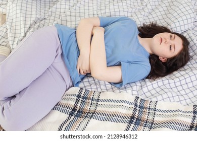 teen girl with stomachache on bed