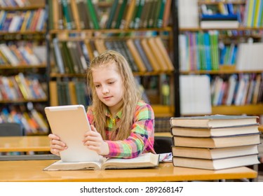 Teen girl with tablet computer working in library