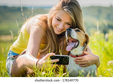 Teen girl taking photo of herself and her dog with mobile phone camera