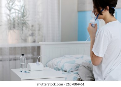 A teen girl using nebulizer inhalation at home. The concept of self-treatment of the respiratory tract using inhalation nebulizer.   Inhaling fumes spray the medication.