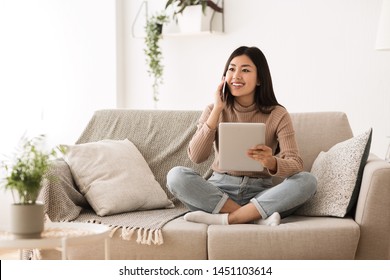 Teen Girl Using Tablet And Talking On Phone With Friend At Home, Copy Space