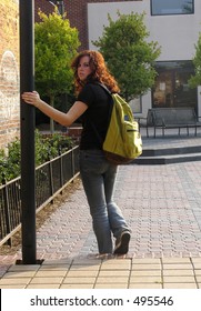 Teen Girl Walking Downtown With A Bookbag Looking Back Toward Camera