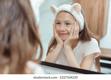 Teen girl washing face in morning in bathroom. Self Care morning bathroom routine child portrait reflection in mirror - Powered by Shutterstock