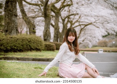 Teen girl wearing a short skirt poses with cherry blossoms in Japan.