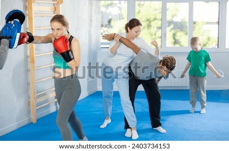 Teen girl works out strength and speed of boxing punch mitts with help of male partner in boxing paws. Man performs role of target and mannequins during training strike technique Stock photo © 